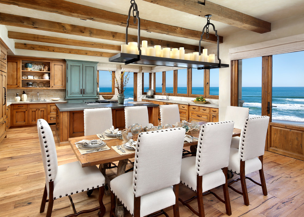 Cette photo montre une salle à manger ouverte sur la cuisine bord de mer de taille moyenne avec un mur blanc, un sol en bois brun, aucune cheminée et un sol marron.