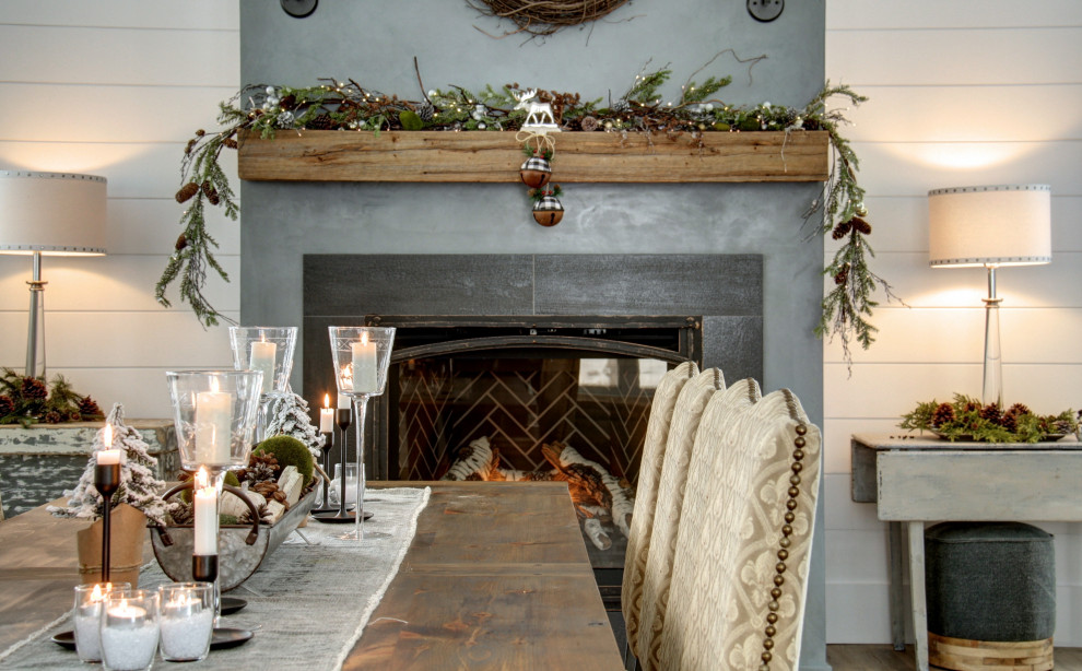 Cette photo montre une grande salle à manger ouverte sur la cuisine nature avec un mur blanc, un sol en bois brun, une cheminée standard et un manteau de cheminée en béton.