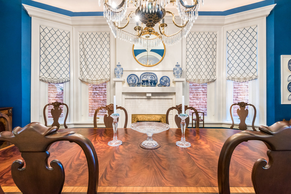 Пример оригинального дизайна: большая отдельная столовая в классическом стиле с синими стенами, темным паркетным полом, стандартным камином и фасадом камина из плитки