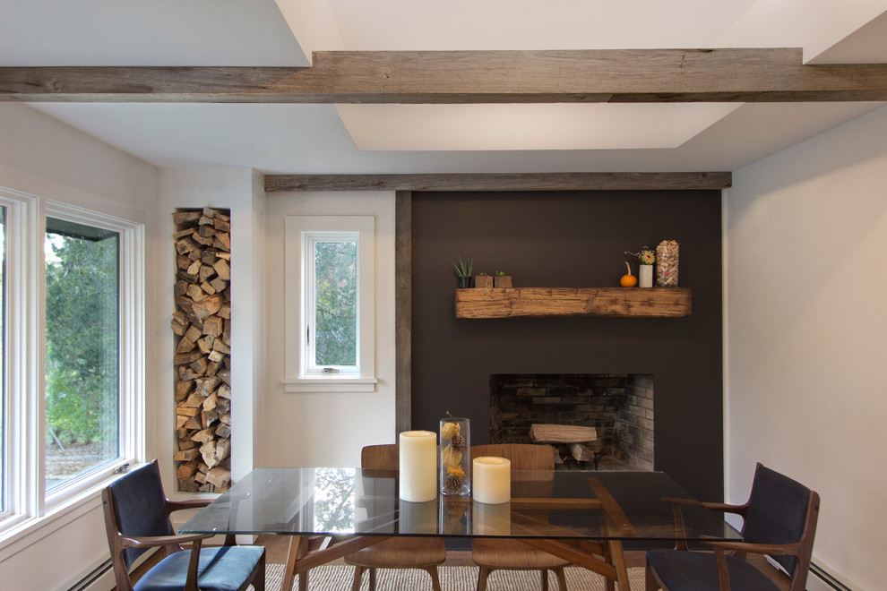 Ispirazione per una sala da pranzo aperta verso la cucina minimal di medie dimensioni con pareti bianche, pavimento in legno massello medio e camino classico