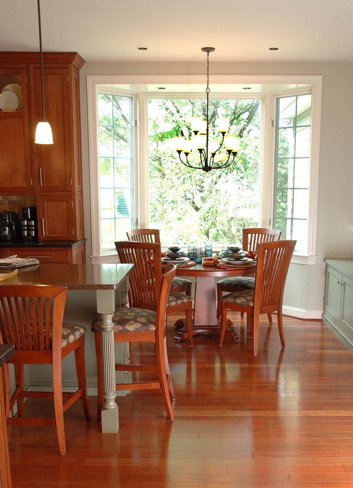Foto di una grande sala da pranzo aperta verso la cucina classica con pareti grigie, pavimento in legno massello medio e camino sospeso