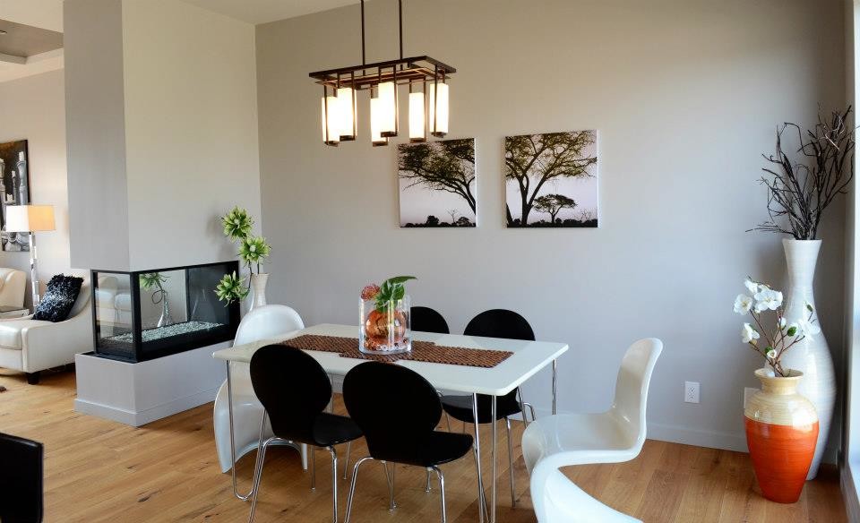 Esempio di una sala da pranzo aperta verso la cucina minimal di medie dimensioni con pareti grigie, parquet chiaro, camino bifacciale e cornice del camino in intonaco