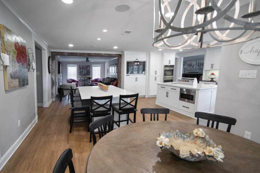 Immagine di una grande sala da pranzo aperta verso la cucina minimalista con pareti grigie, pavimento in legno massello medio e pavimento marrone