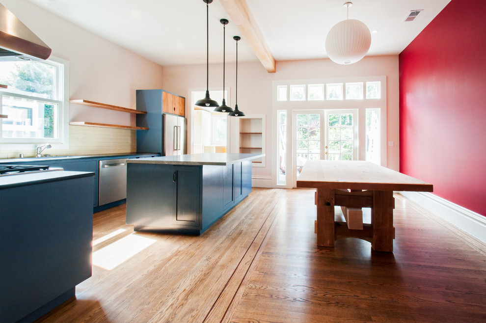 Réalisation d'une salle à manger ouverte sur la cuisine design avec un mur rouge et un sol en bois brun.