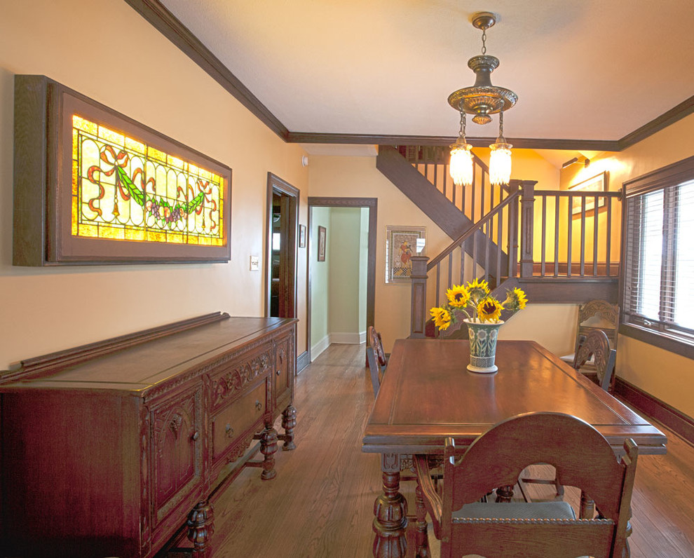Example of a mid-sized country dark wood floor and brown floor enclosed dining room design in Cleveland with beige walls and no fireplace