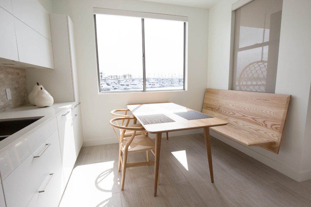 Réalisation d'une petite salle à manger ouverte sur la cuisine minimaliste avec un mur blanc, parquet clair et un sol gris.