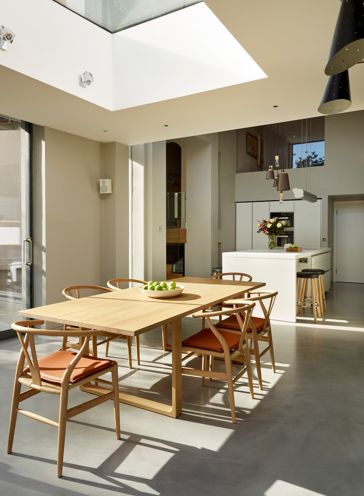 Ispirazione per una sala da pranzo aperta verso la cucina design con pareti grigie e pavimento in cemento