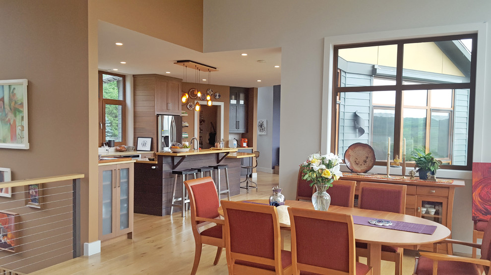 Exemple d'une salle à manger ouverte sur le salon tendance de taille moyenne avec un mur beige, parquet clair et une cheminée standard.