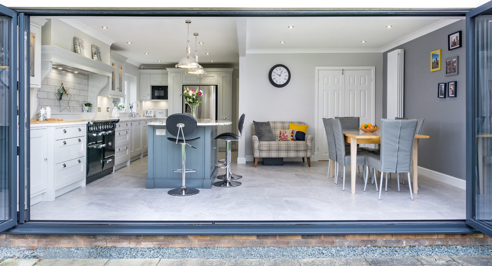 This is an example of a large traditional grey and white single-wall kitchen/diner in Other with grey floors, a built-in sink, shaker cabinets, grey cabinets, engineered stone countertops, white splashback, ceramic splashback, black appliances, ceramic flooring, an island and white worktops.