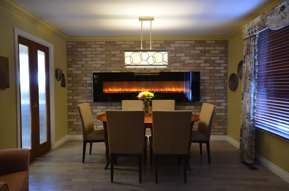 Cette photo montre une petite salle à manger chic fermée avec un mur beige, parquet clair, cheminée suspendue et un manteau de cheminée en brique.