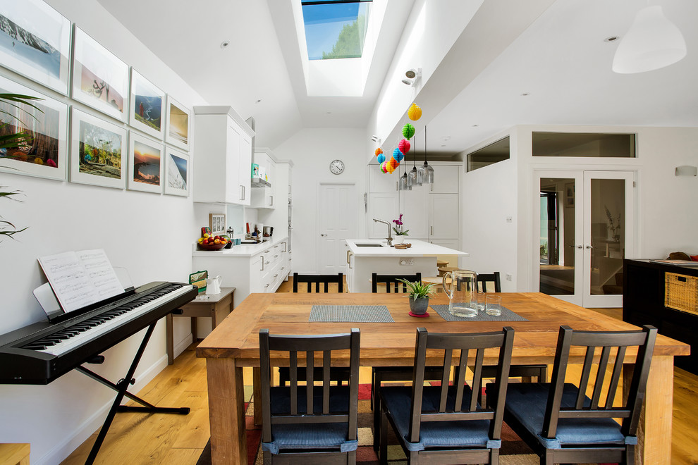 Idee per una sala da pranzo aperta verso il soggiorno minimal di medie dimensioni con pareti bianche, pavimento in legno massello medio e pavimento marrone