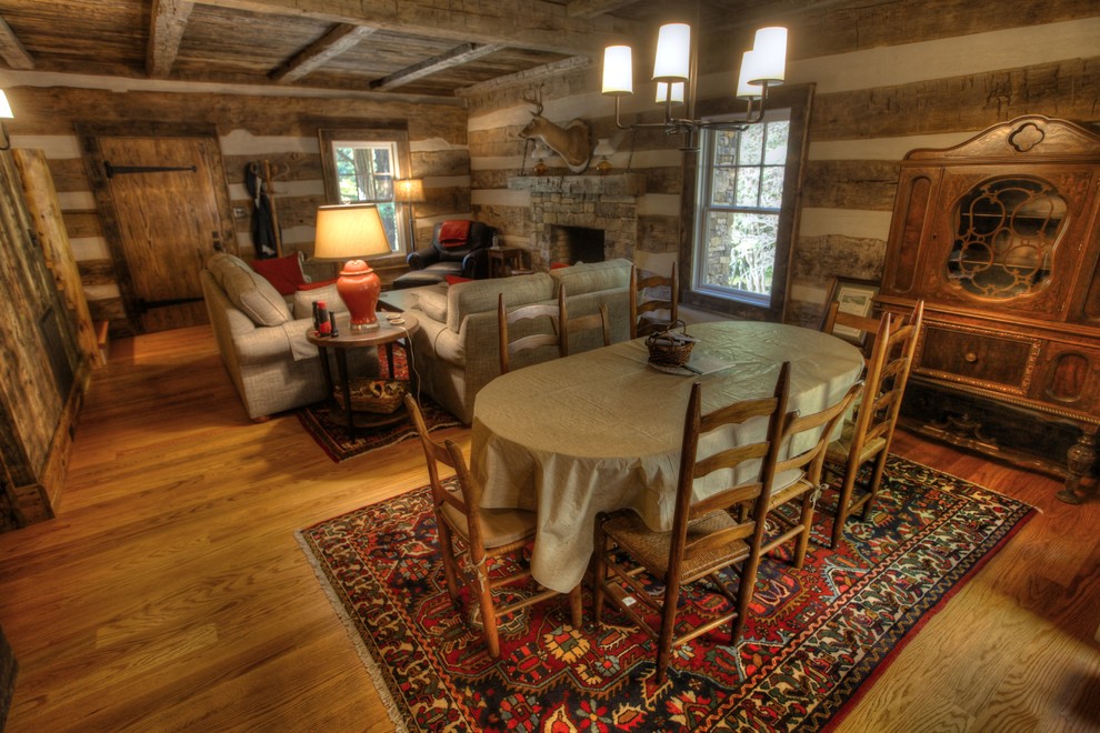Foto di una piccola sala da pranzo aperta verso il soggiorno rustica con pareti marroni, parquet chiaro, camino classico e cornice del camino in pietra