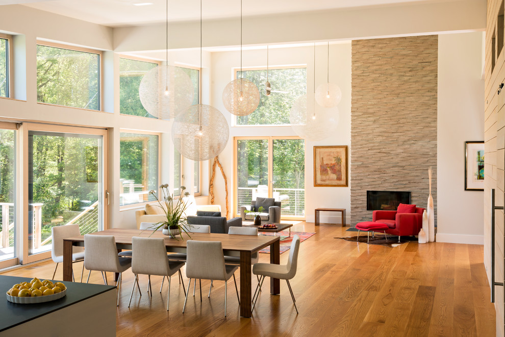 Große Moderne Wohnküche mit beiger Wandfarbe, braunem Holzboden, Kamin, Kaminumrandung aus Stein und beigem Boden in Boston