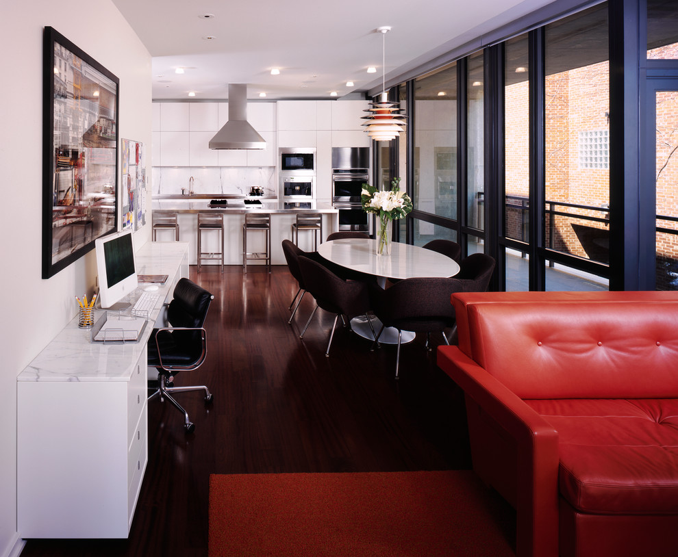 Immagine di una sala da pranzo aperta verso il soggiorno minimalista con pareti bianche e parquet scuro