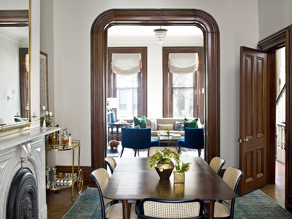 Photo of a traditional dining room in Chicago with white walls, medium hardwood flooring, a wood burning stove, a stone fireplace surround and brown floors.