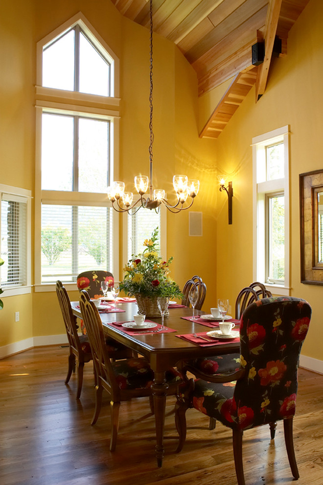 Idées déco pour une salle à manger classique avec un mur jaune, un sol en bois brun et un sol marron.