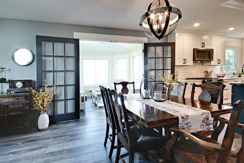 Cette image montre une salle à manger ouverte sur la cuisine rustique de taille moyenne avec un mur gris, un sol en vinyl, aucune cheminée et un sol gris.
