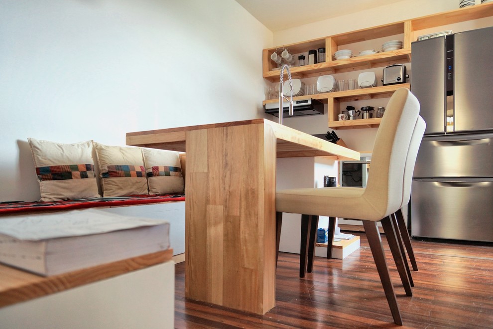 Immagine di una piccola sala da pranzo aperta verso il soggiorno tropicale con pareti bianche e pavimento in legno massello medio
