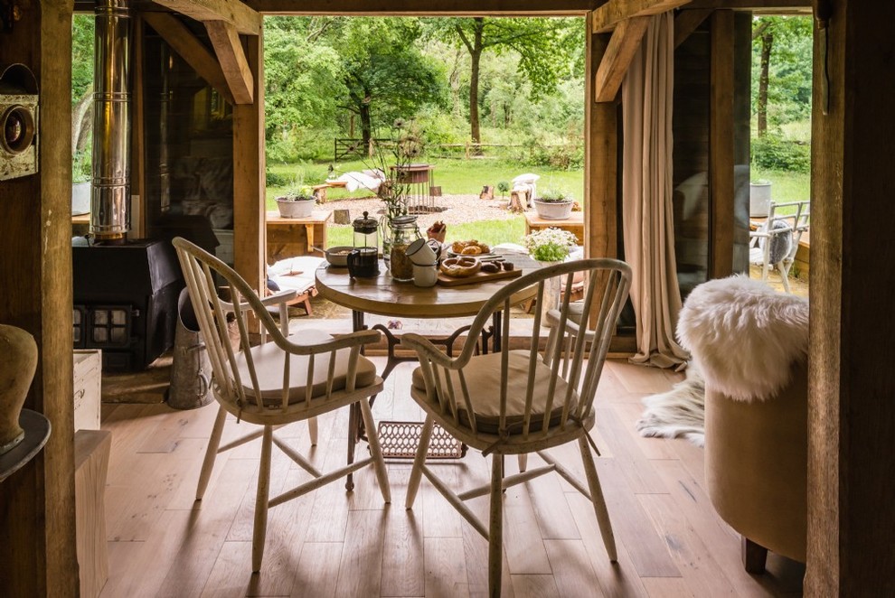 Aménagement d'une salle à manger ouverte sur le salon montagne de taille moyenne avec un mur blanc, parquet clair, un poêle à bois, un manteau de cheminée en bois et un sol beige.