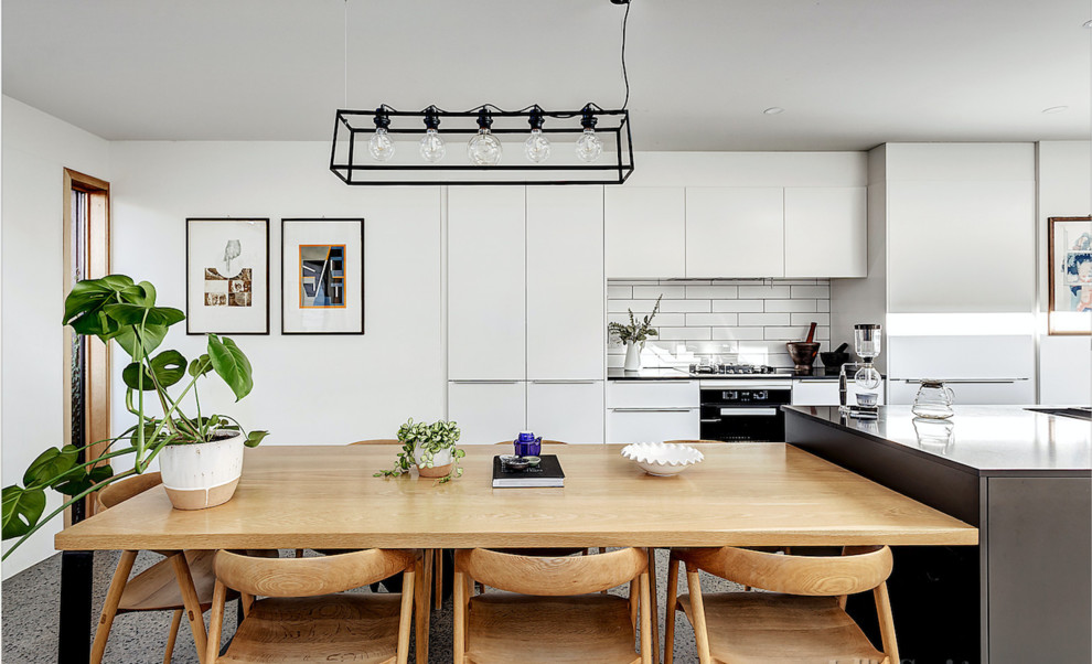 Cette photo montre une salle à manger ouverte sur la cuisine tendance de taille moyenne avec un mur blanc et un sol gris.