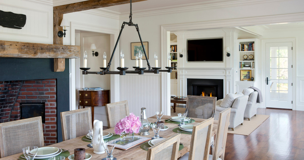 Imagen de comedor clásico de tamaño medio abierto con paredes blancas, suelo de madera en tonos medios, todas las chimeneas y marco de chimenea de metal