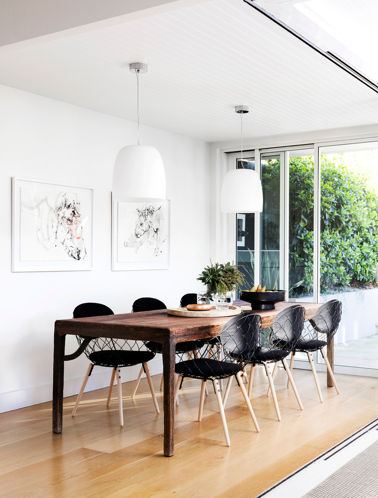 Cette image montre une petite salle à manger ouverte sur le salon design avec un mur blanc et parquet clair.