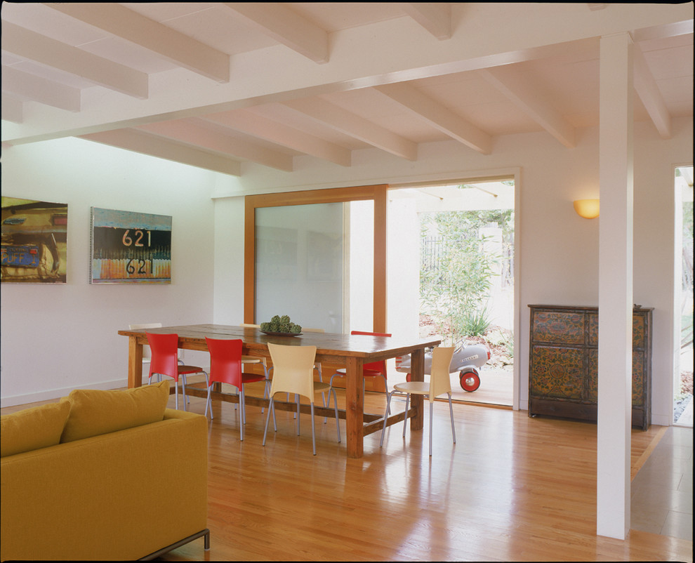 Aménagement d'une salle à manger moderne avec un mur blanc et un sol en bois brun.