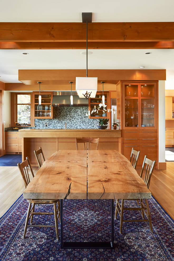 Cette photo montre une salle à manger tendance avec un mur blanc et un sol en bois brun.