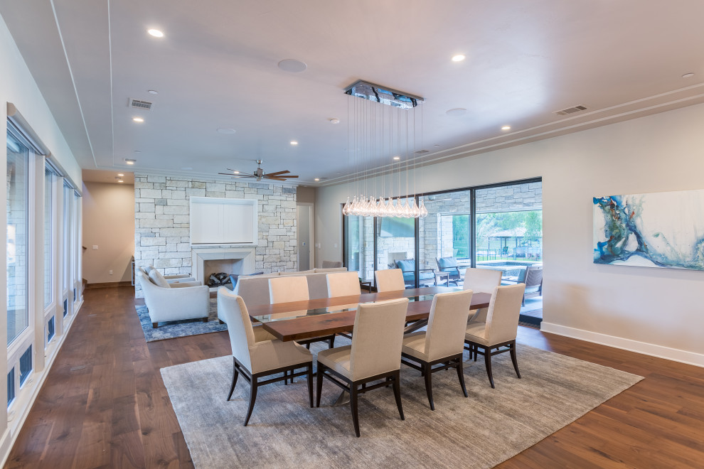 This is an example of a medium sized modern kitchen/dining room in Austin with grey walls, medium hardwood flooring, a standard fireplace, a stone fireplace surround, brown floors and a drop ceiling.