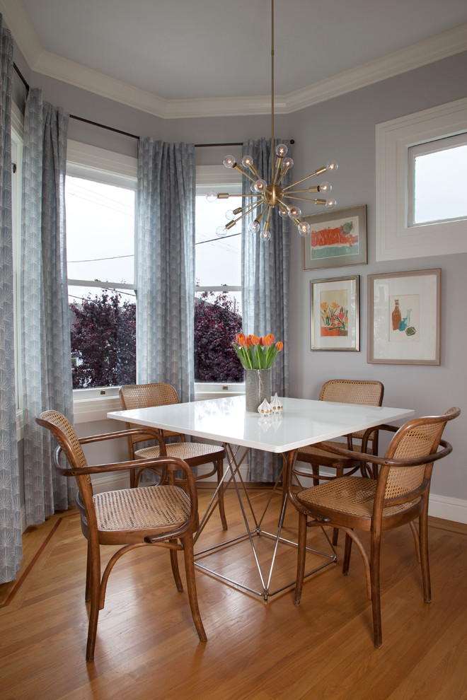 Immagine di una sala da pranzo aperta verso la cucina tradizionale con pareti grigie e pavimento in legno massello medio