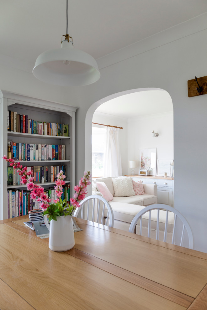 Cette image montre une petite salle à manger ouverte sur le salon avec un mur blanc, moquette et un manteau de cheminée en plâtre.