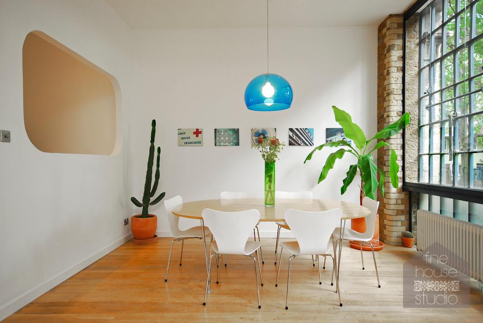 Ispirazione per una sala da pranzo aperta verso la cucina industriale di medie dimensioni con pareti bianche e parquet chiaro