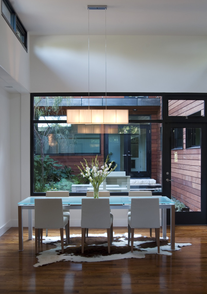 Imagen de comedor minimalista de tamaño medio abierto con paredes blancas y suelo de madera oscura