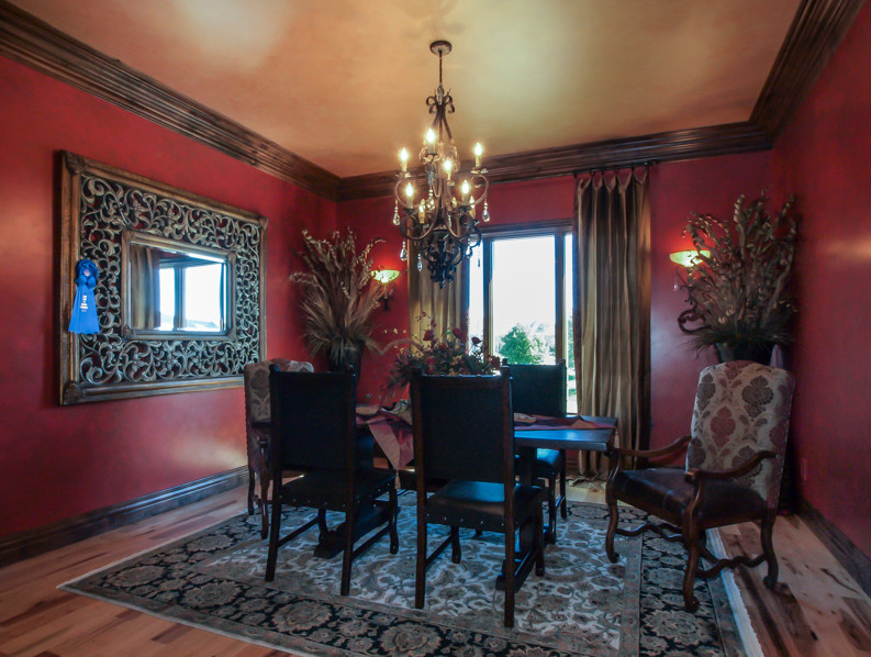 Esempio di una sala da pranzo rustica chiusa e di medie dimensioni con pareti rosse, parquet chiaro e nessun camino