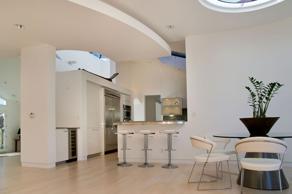 Idee per una sala da pranzo aperta verso la cucina minimalista con pareti bianche e parquet chiaro