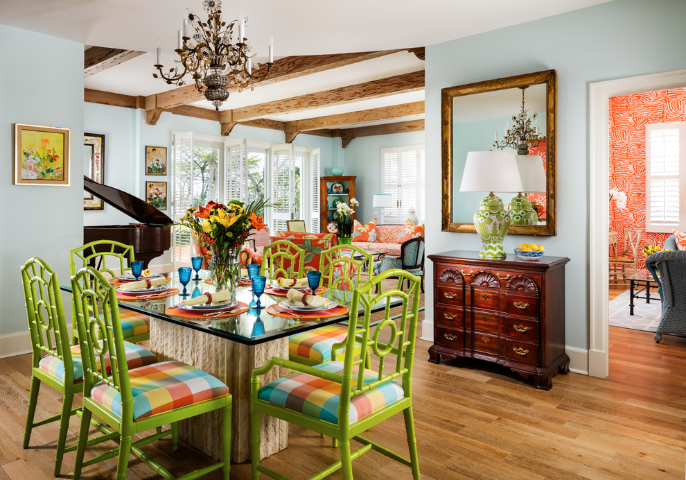 Aménagement d'une grande salle à manger ouverte sur le salon exotique avec un mur bleu, parquet clair et un sol marron.