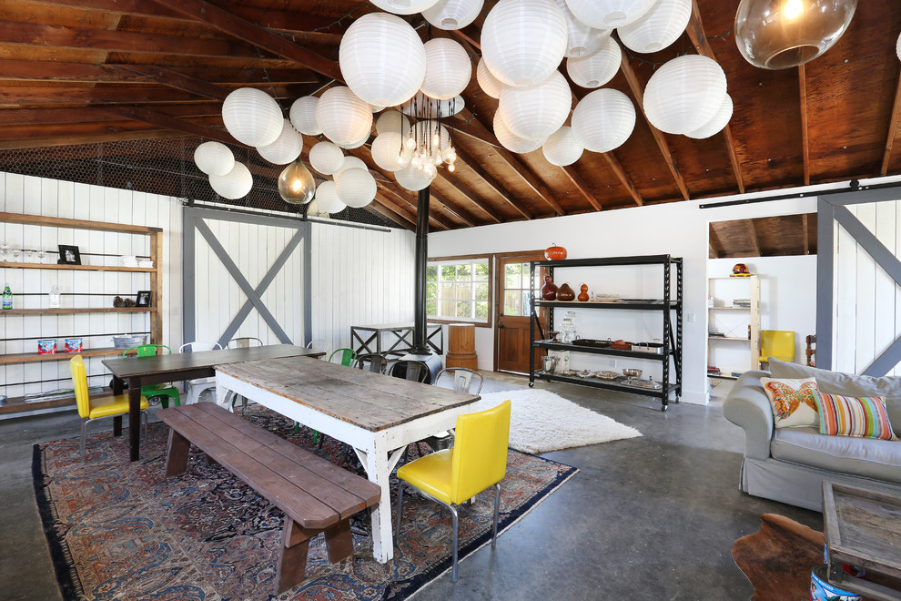 Foto di una grande sala da pranzo aperta verso il soggiorno tropicale con pareti bianche e pavimento in cemento