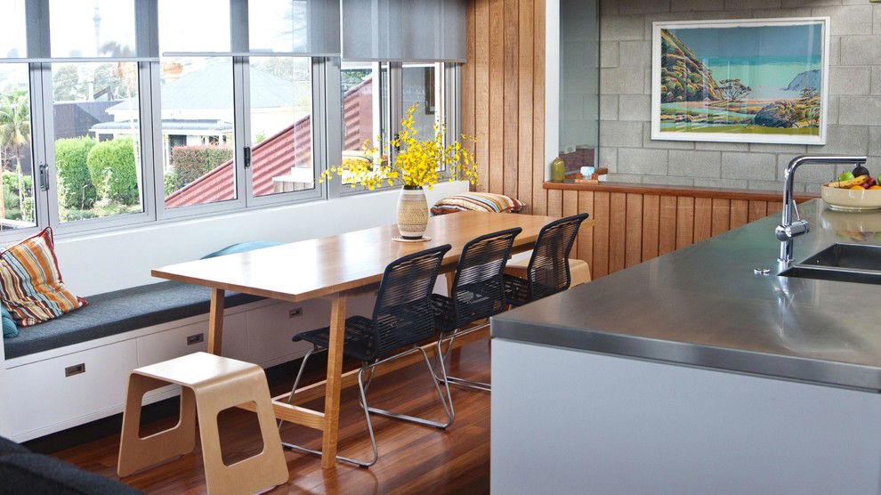 Cette image montre une salle à manger ouverte sur la cuisine minimaliste avec un sol en bois brun.