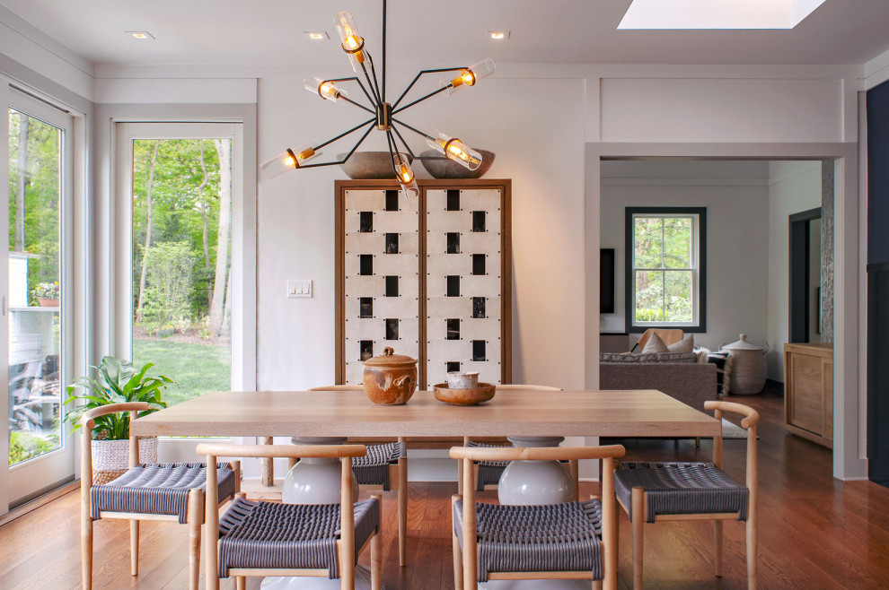 Cette photo montre une salle à manger moderne avec un mur blanc, parquet foncé et un sol marron.