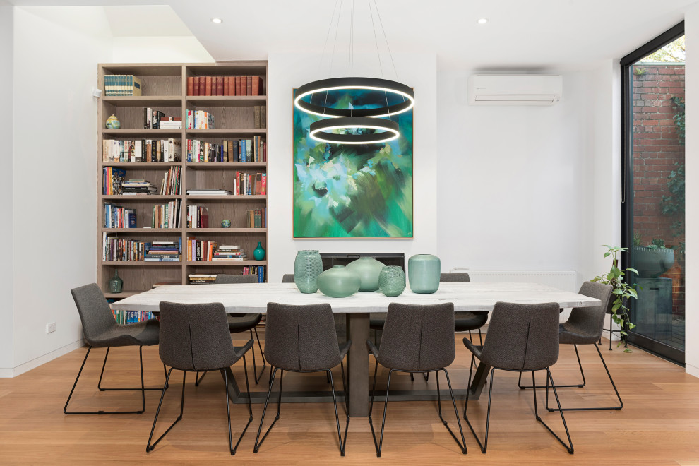Inspiration for a contemporary medium tone wood floor and brown floor dining room remodel in Melbourne with white walls and a standard fireplace