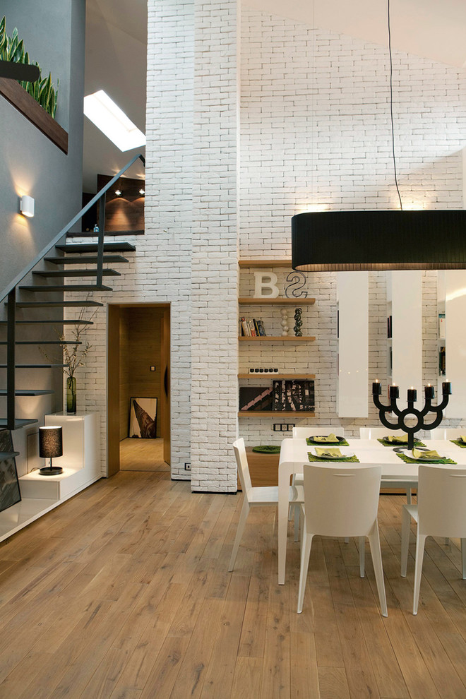 Idée de décoration pour une salle à manger design avec un mur blanc et un sol en bois brun.