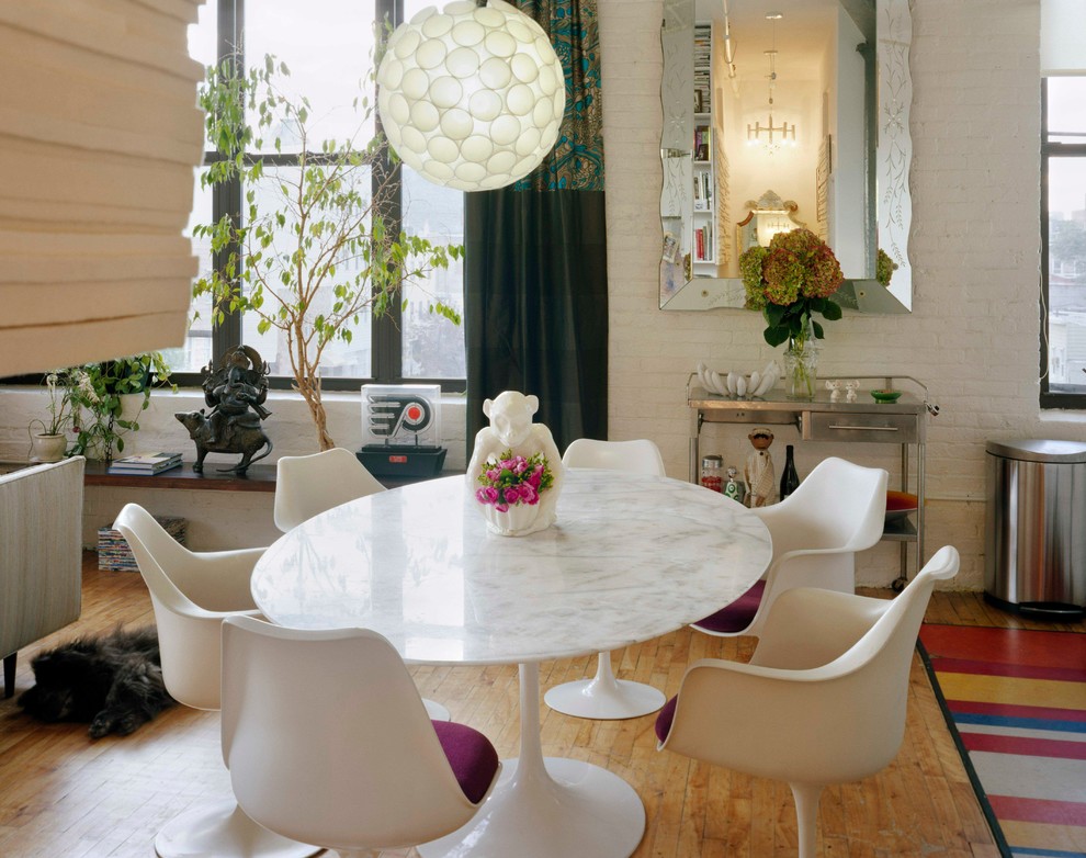 Photo of an eclectic dining room in New York with white walls and medium hardwood flooring.