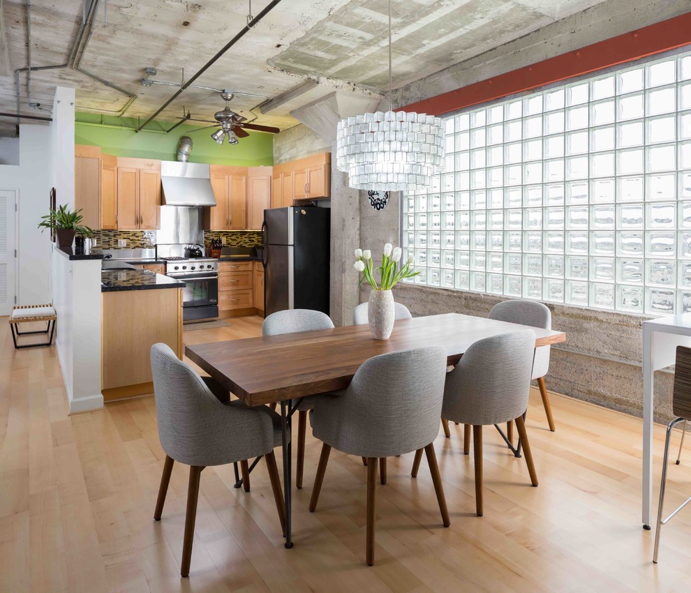 Foto di una sala da pranzo aperta verso la cucina industriale con parquet chiaro