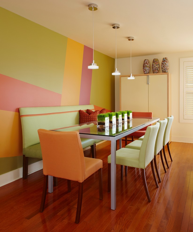 Cette image montre une salle à manger design avec un mur multicolore et un sol en bois brun.