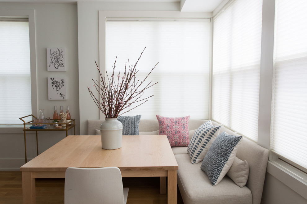 Cette image montre une petite salle à manger ouverte sur la cuisine minimaliste avec un mur blanc, un sol en bois brun et un sol marron.
