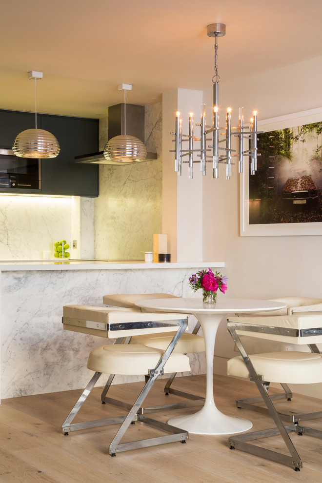 Cette image montre une salle à manger ouverte sur la cuisine design avec un mur blanc et parquet clair.