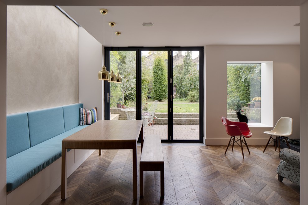 This is an example of a medium sized kitchen/dining room in London with white walls, medium hardwood flooring and no fireplace.