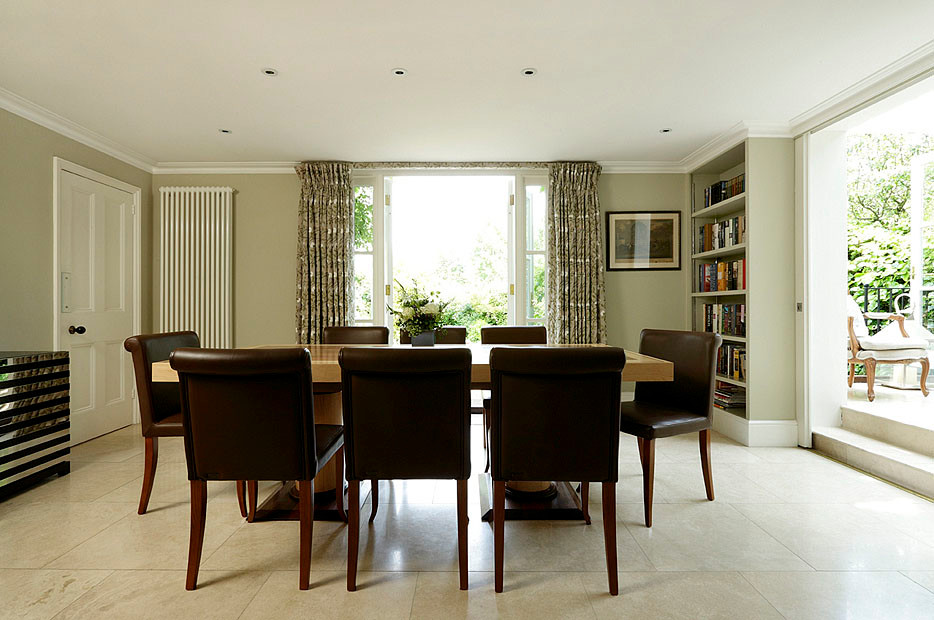 Large classic kitchen/dining room in London with green walls and limestone flooring.