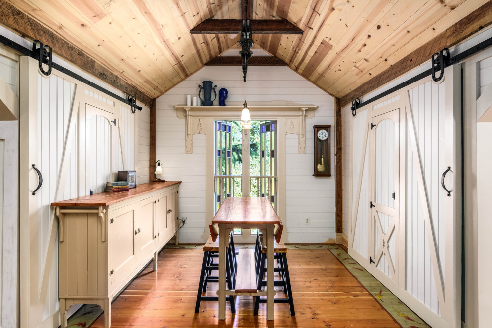 Modelo de comedor abovedado de estilo de casa de campo con paredes blancas, suelo de madera en tonos medios, suelo marrón, madera y machihembrado
