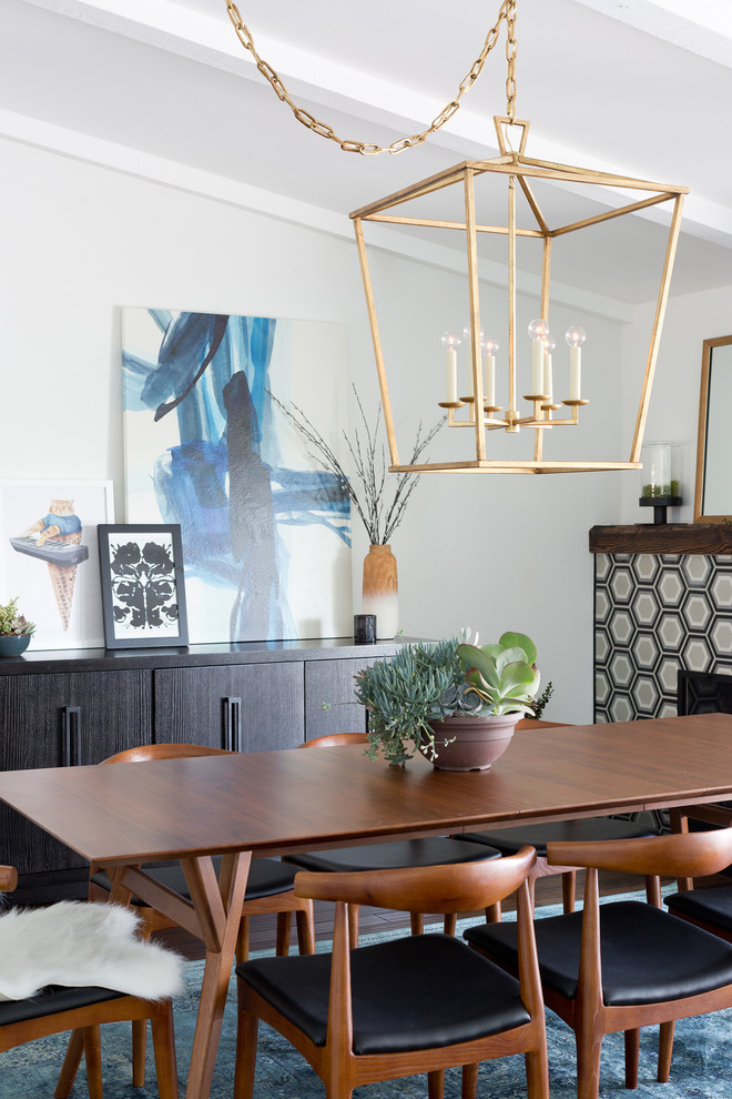 Immagine di una sala da pranzo aperta verso la cucina minimalista di medie dimensioni con pareti bianche, parquet scuro, camino classico e cornice del camino piastrellata